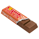A partially unwrapped Tony's Chocolonely caramel and sea salt chocolate bar with a orange and white wrapper.